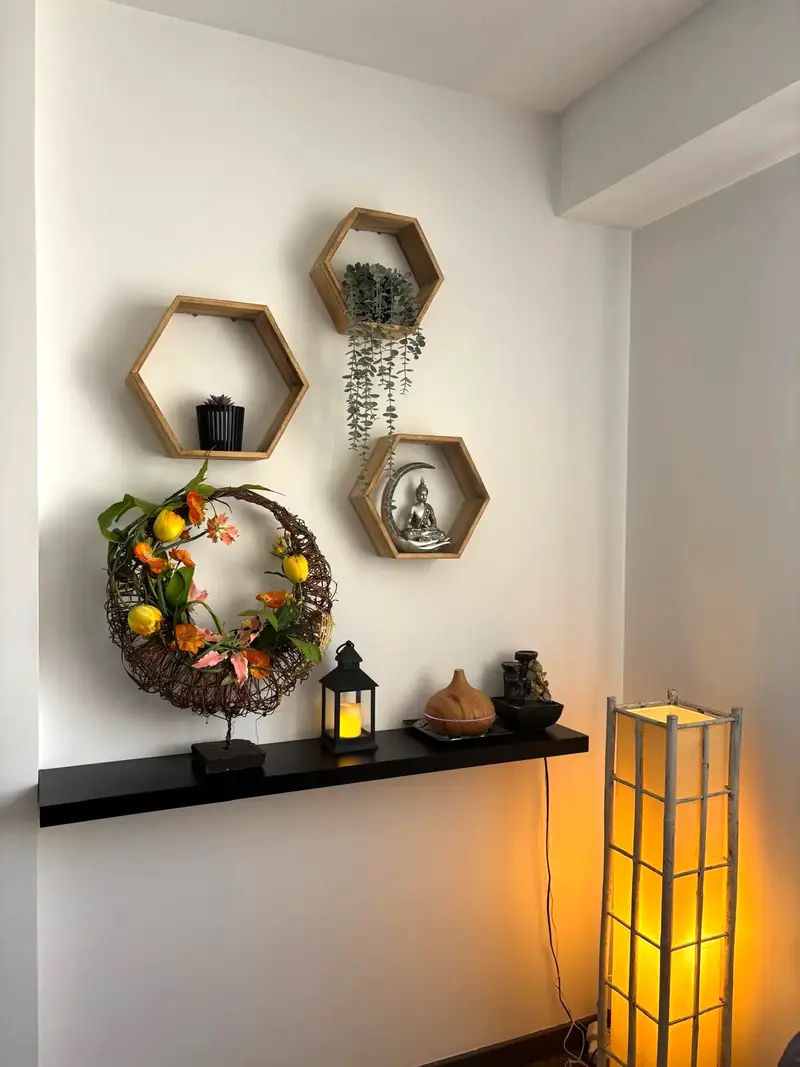 Rincón del centro con estantes hexagonales, una corona de flores y una lámpara encendida